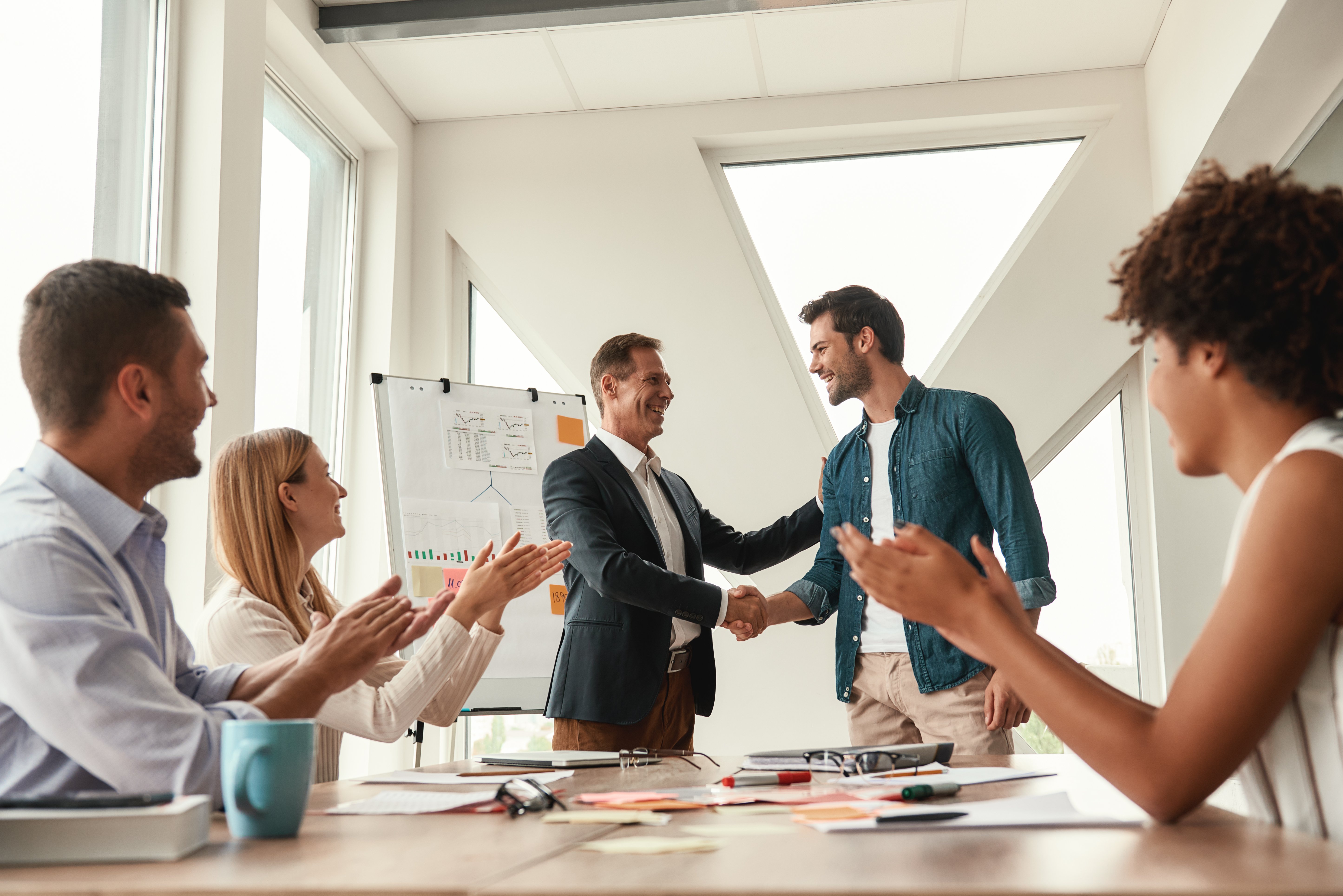 welcome-our-team-two-cheerful-colleagues-shaking-hands-smiling-while-having-meeting